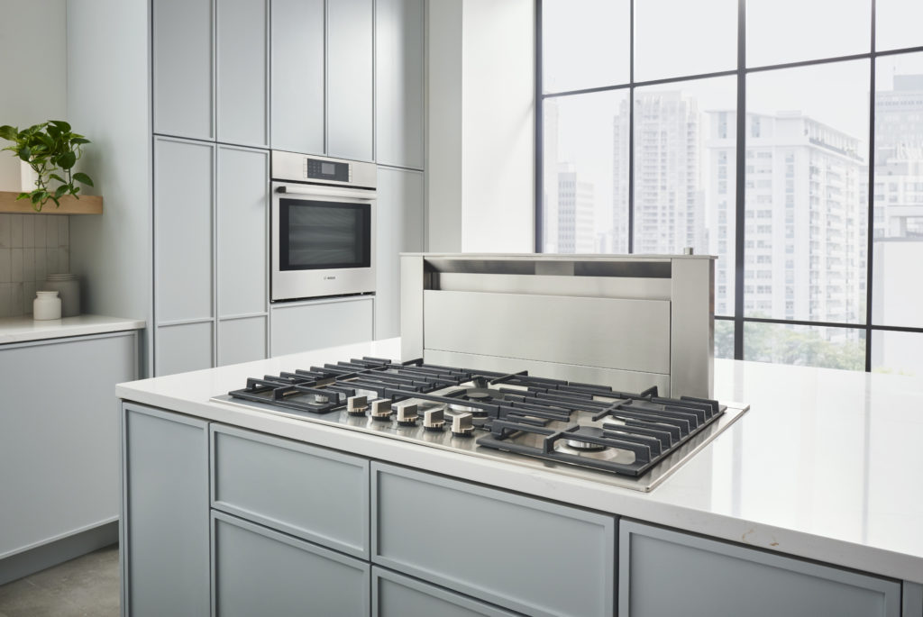 Modern kitchen with Bosch appliances and pale blue cabinets.