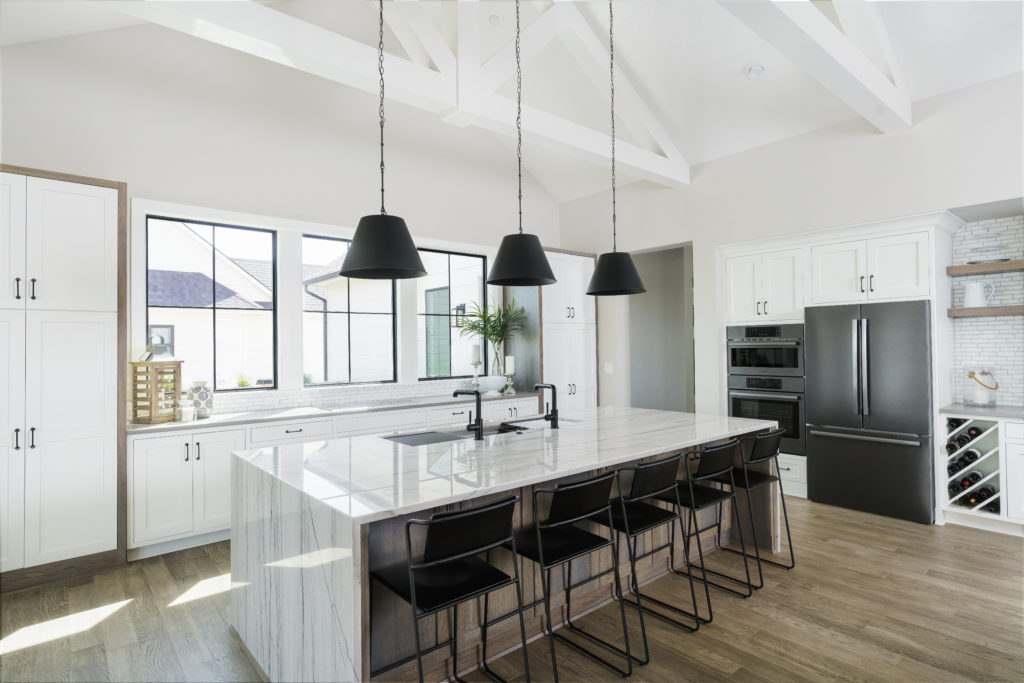 White kitchen with black accents, Bosch appliances and marble waterfall kitchen island.